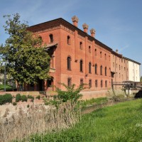 Mulino di Bentivoglio, complesso abitativo e molitorio oggi; in primo piano il palazzo Rosso sede del marchese Pizzardi, proprietario del mulino. La forma a prua del giardino anteriore è voluta: qui il canale Navile si divideva in due rami dando origine al porto di Bentivoglio (non più esistente). Subito dietro una unità condominiale e in fondo, intonacato di bianco, il lato est dell’opificio, Massimo Brunelli - Associazione Amici delle Vie d’Acqua e dei Sotterranei di Bologna / Bologna sotterranea®.